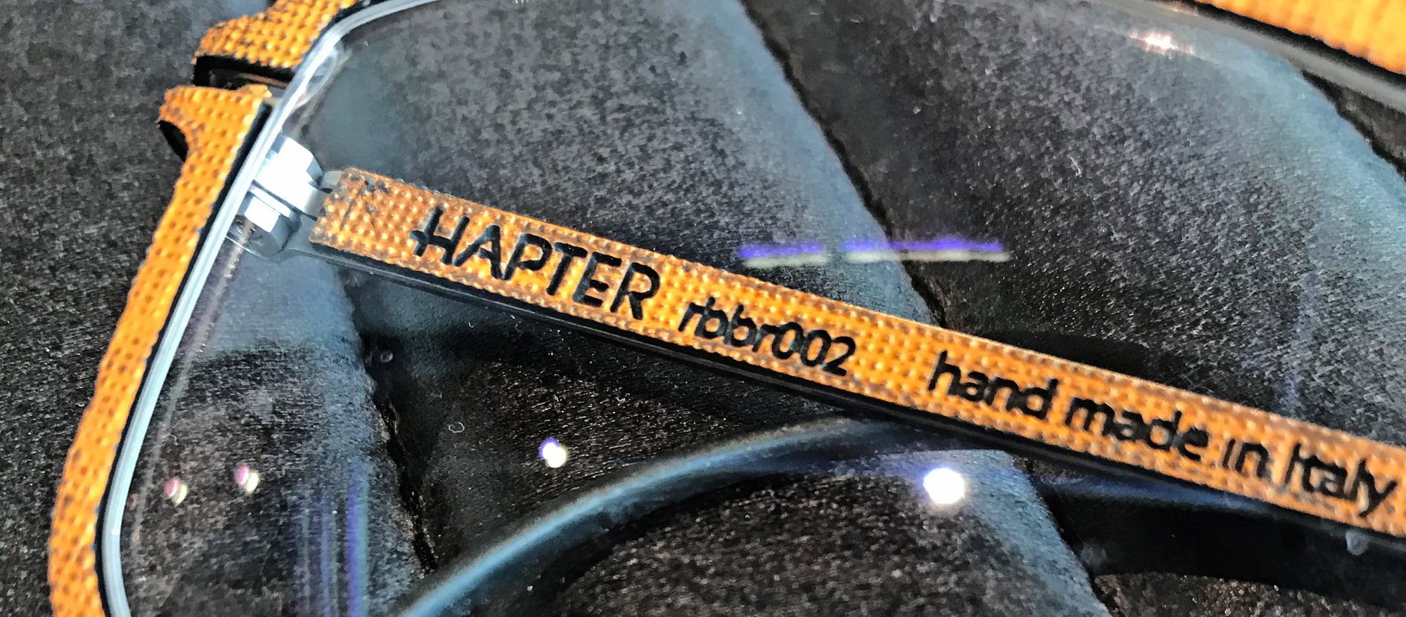 Detail of a Hapter frame with an orange textile-wrapped temple, hand made in Italy.